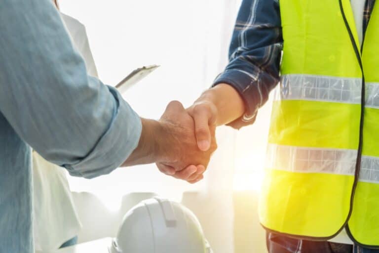 Contractor and construction worker shake hands after a project planning meeting