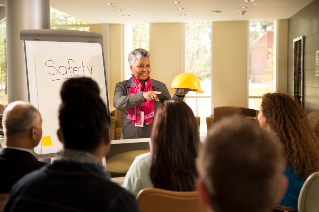 A female construction professional gives a talk on construction site safety to a group of individuals